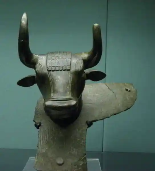 A winged bull head with wings from a large cauldron